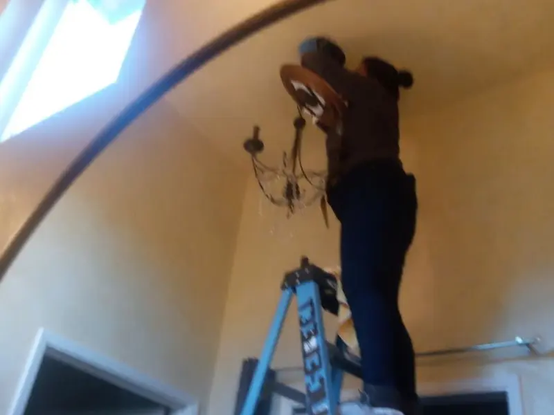 Electrician installing a chandelier in a Festus residence